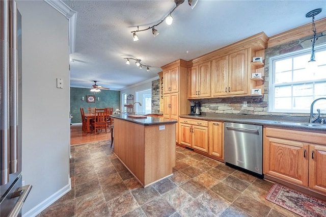 kitchen featuring dishwasher, dark countertops, a sink, a ceiling fan, and baseboards