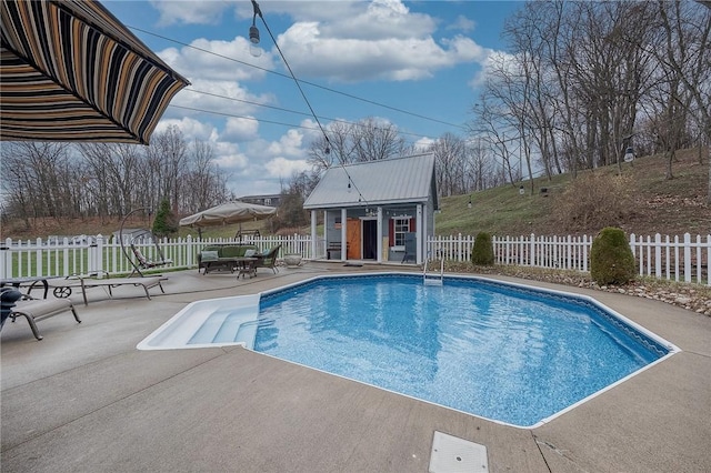 view of swimming pool featuring a patio, an outbuilding, a fenced backyard, and a storage structure