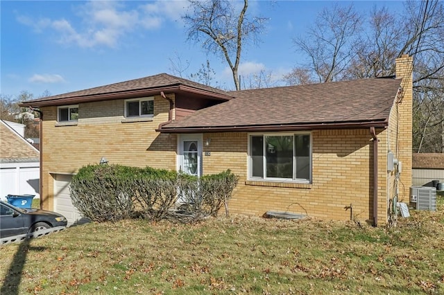 view of front facade with brick siding, a chimney, central AC unit, and a front yard