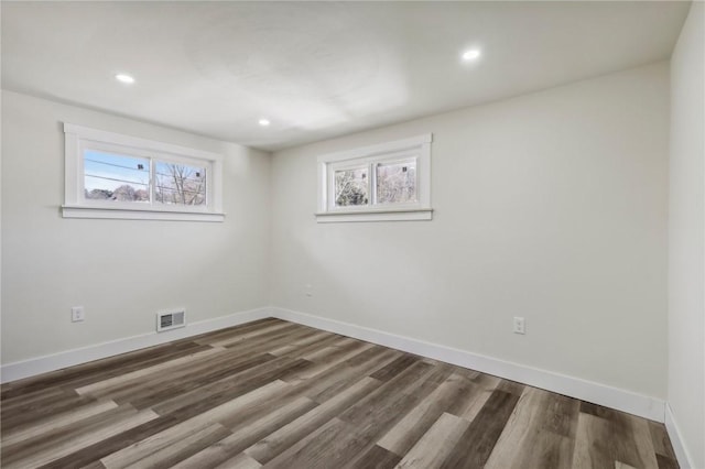 spare room featuring baseboards, visible vents, wood finished floors, and a healthy amount of sunlight