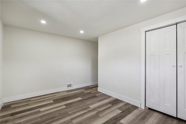 unfurnished bedroom with a closet, visible vents, baseboards, wood finished floors, and recessed lighting