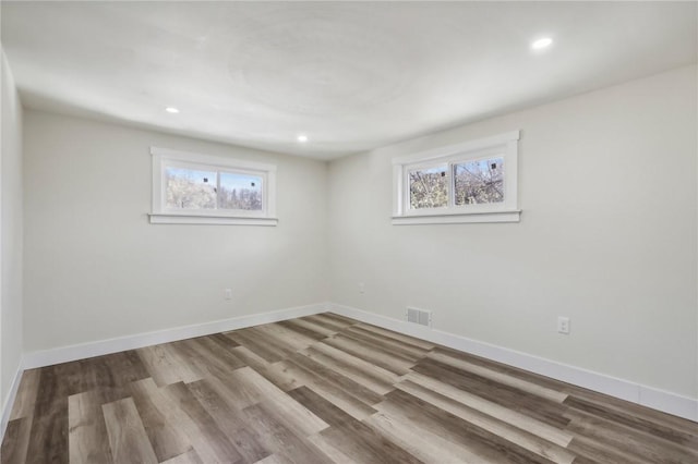 spare room with wood finished floors, baseboards, a healthy amount of sunlight, and visible vents