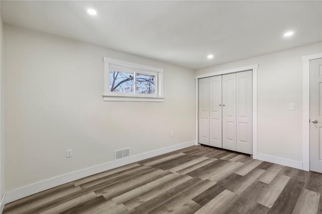 unfurnished bedroom featuring wood finished floors, recessed lighting, baseboards, and visible vents