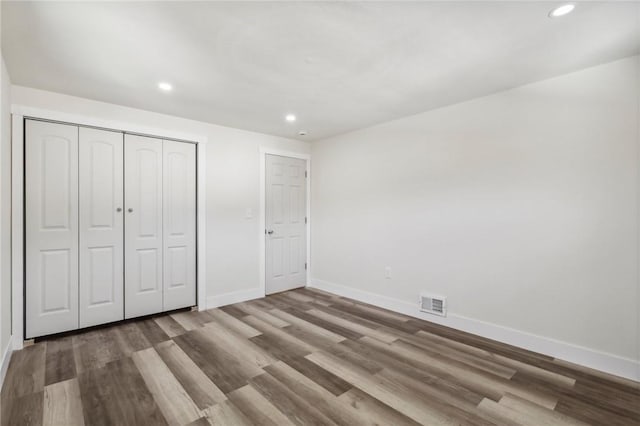 unfurnished bedroom featuring baseboards, visible vents, and wood finished floors