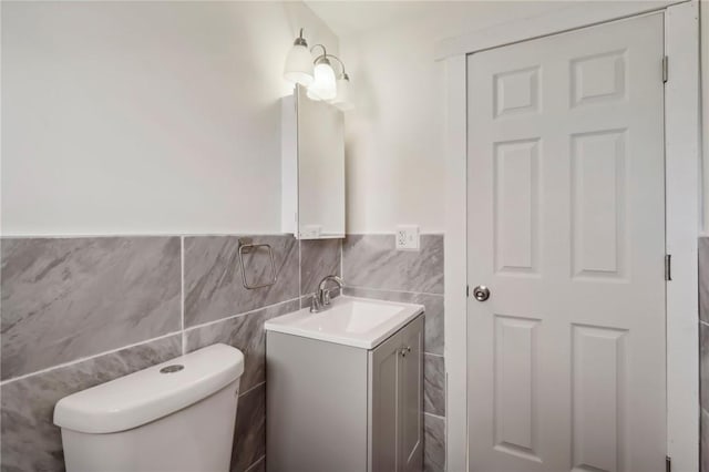 half bath featuring tile walls, toilet, and vanity