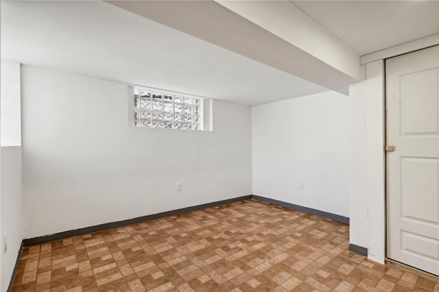 below grade area featuring baseboards and light floors