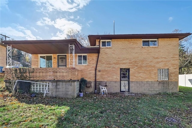 rear view of house with a lawn and brick siding