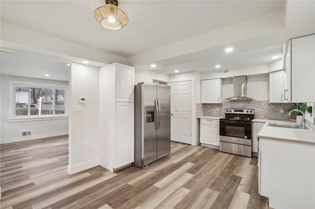 kitchen featuring backsplash, a sink, wall chimney exhaust hood, stainless steel appliances, and visible vents
