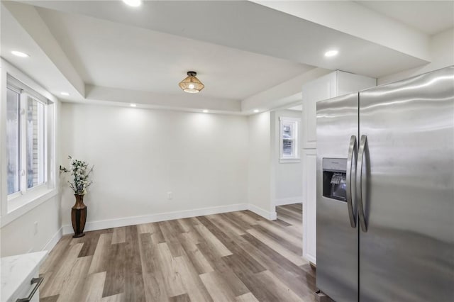 interior space with stainless steel refrigerator with ice dispenser, light wood-style flooring, recessed lighting, baseboards, and white cabinets