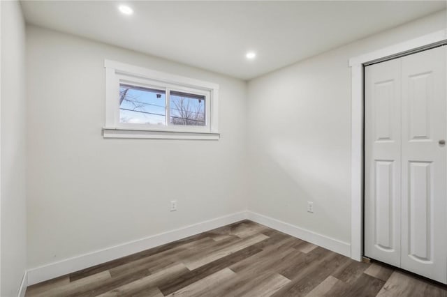 unfurnished bedroom featuring a closet, dark wood-type flooring, baseboards, and recessed lighting