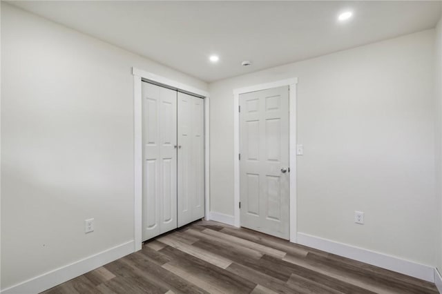 unfurnished bedroom featuring baseboards, a closet, wood finished floors, and recessed lighting