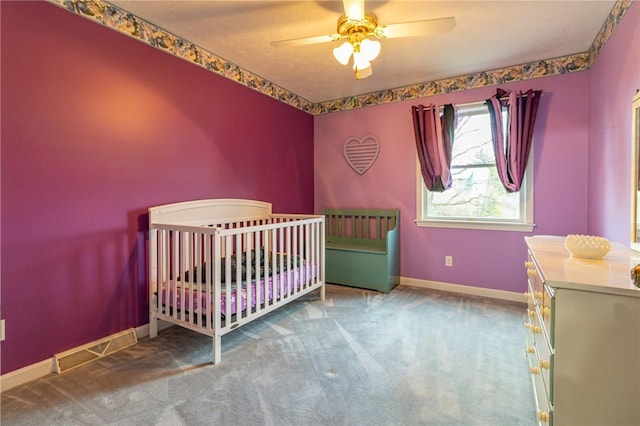 carpeted bedroom with a nursery area, visible vents, baseboards, and ceiling fan