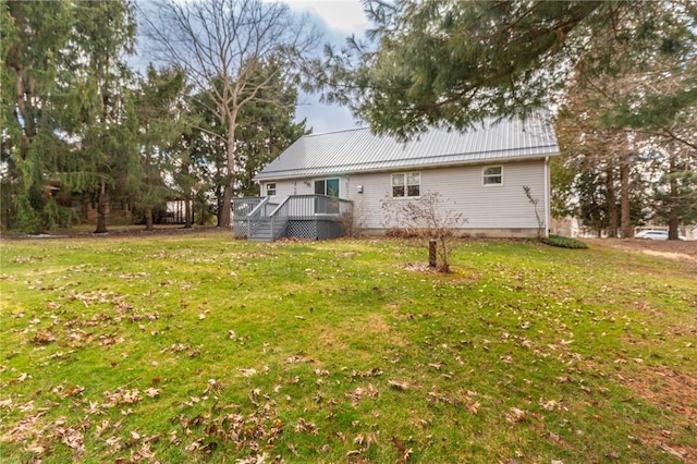 rear view of property with a lawn, metal roof, and a deck