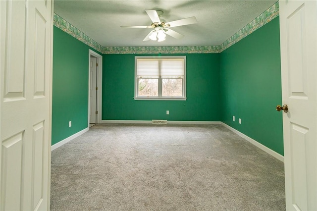 unfurnished room with baseboards, visible vents, carpet, and ceiling fan
