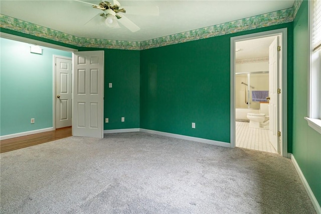 unfurnished bedroom featuring baseboards, a ceiling fan, ensuite bathroom, and carpet