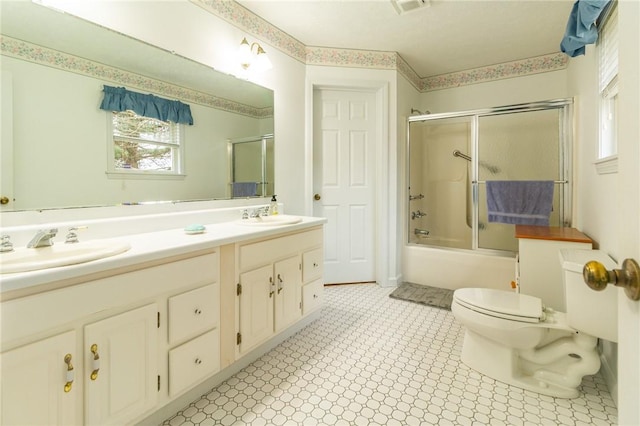 bathroom with toilet, a sink, double vanity, and combined bath / shower with glass door