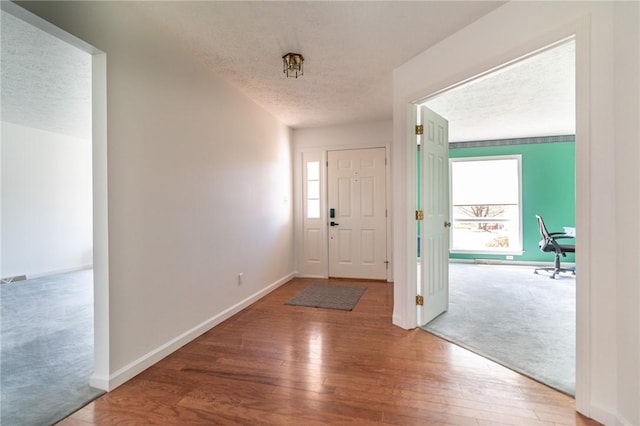 foyer entrance with wood-type flooring, baseboards, and a textured ceiling