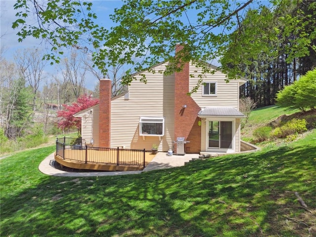 back of property featuring a chimney, a patio, a deck, and a yard