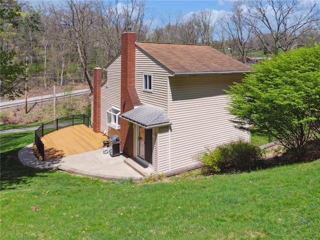 view of side of home featuring a lawn, a shingled roof, and a chimney