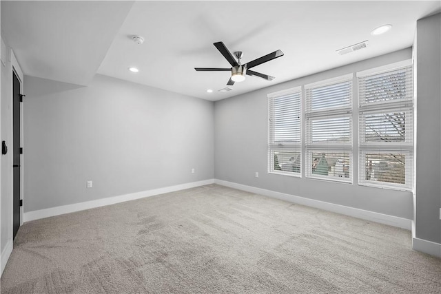 empty room with carpet flooring, a ceiling fan, baseboards, and visible vents
