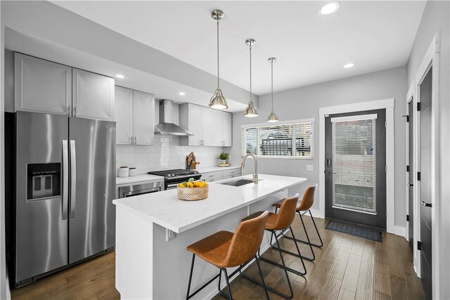 kitchen featuring a sink, wall chimney exhaust hood, appliances with stainless steel finishes, and dark wood-style flooring