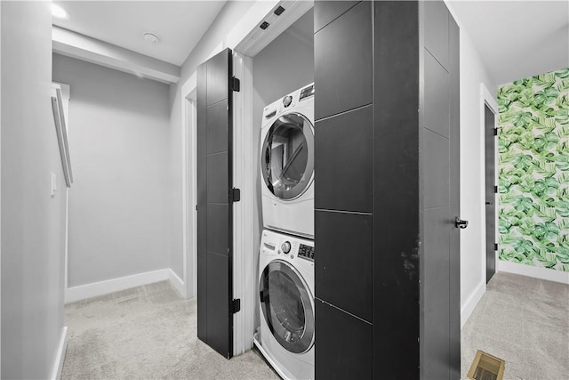 washroom with baseboards, stacked washer and dryer, visible vents, light carpet, and laundry area