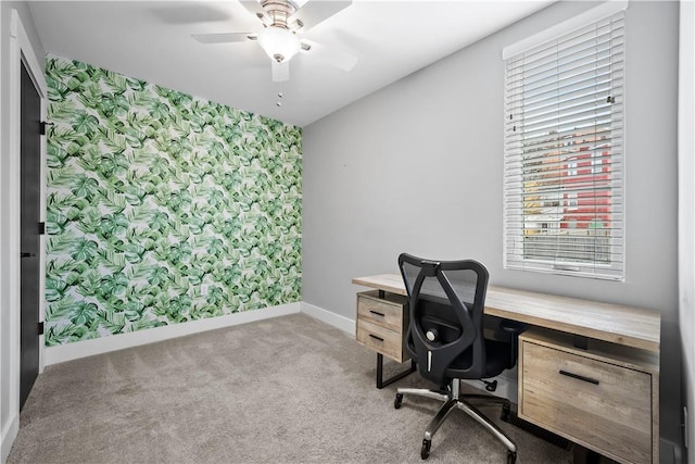 office area with carpet flooring, baseboards, wallpapered walls, a ceiling fan, and an accent wall