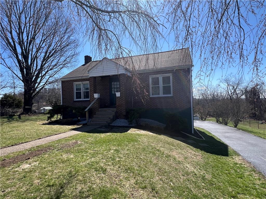 bungalow with a front lawn, a chimney, and brick siding