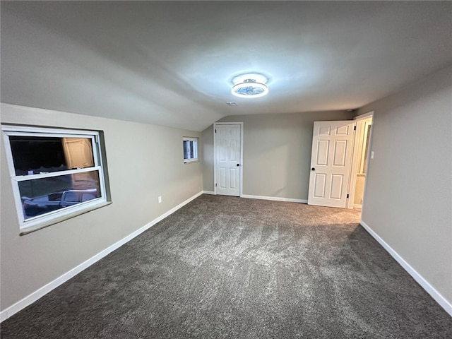 unfurnished bedroom with baseboards, lofted ceiling, and carpet floors