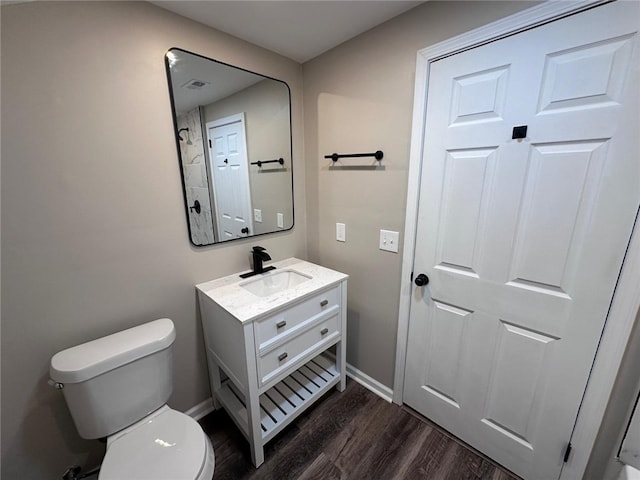 bathroom featuring vanity, toilet, baseboards, visible vents, and wood finished floors