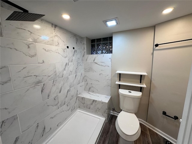 full bathroom featuring a tile shower, wood finished floors, toilet, and recessed lighting