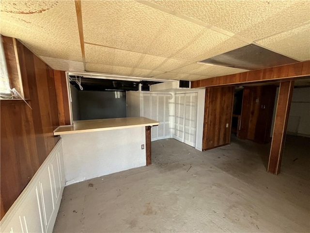 below grade area featuring wood walls and a drop ceiling