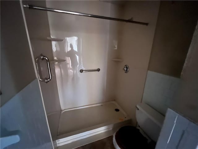 full bathroom featuring toilet and a stall shower