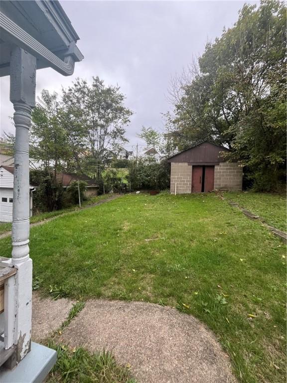 view of green lawn with an outbuilding and a storage unit
