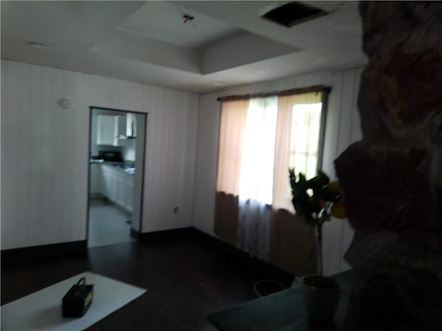 interior space featuring a tray ceiling and dark wood-style flooring