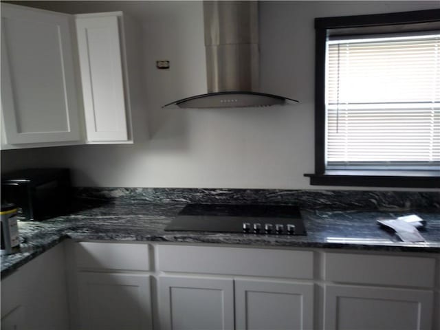kitchen featuring wall chimney range hood, white cabinetry, and black electric stovetop
