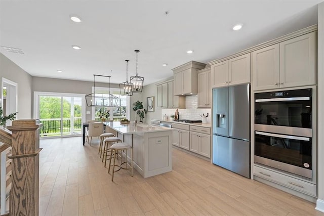 111 Quail Run Rd Unit 1, Peters Twp, PA 15367 - kitchen with appliances with stainless steel finishes, a kitchen breakfast bar, light countertops, light wood-style floors, and backsplash