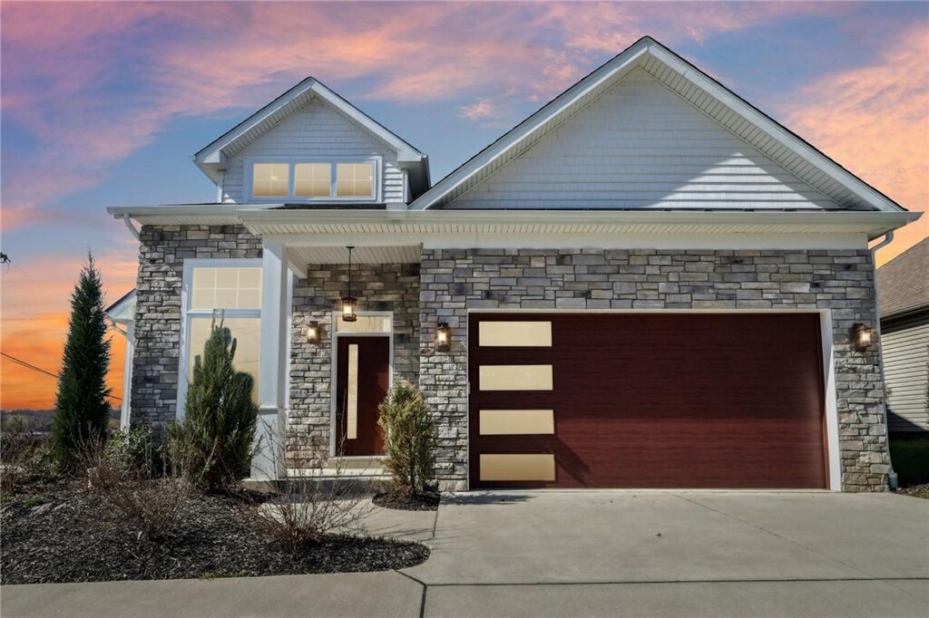 view of front facade with stone siding, an attached garage, and concrete driveway