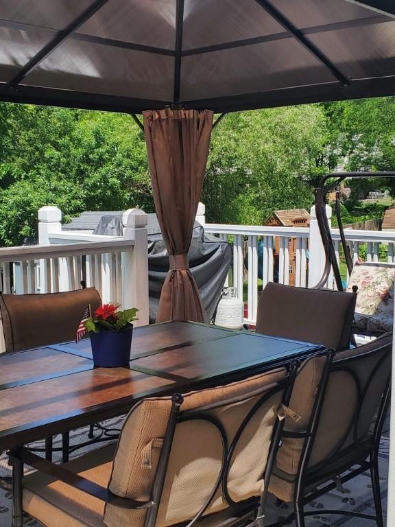wooden deck with a gazebo and outdoor dining area