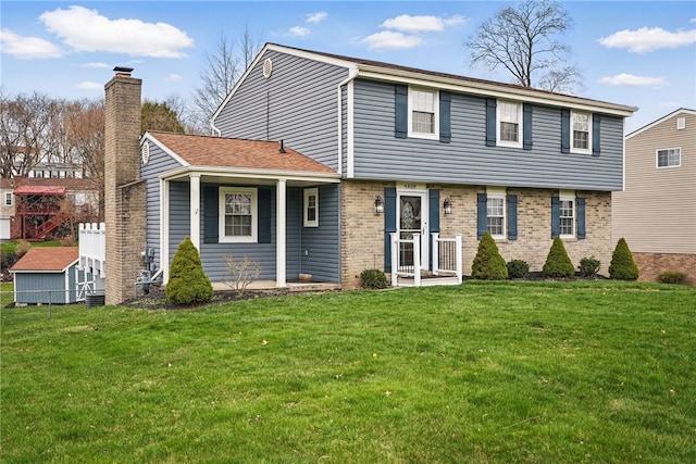 colonial-style house with brick siding, a chimney, and a front lawn