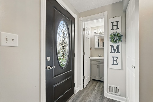 entryway with baseboards, visible vents, and dark wood-style flooring