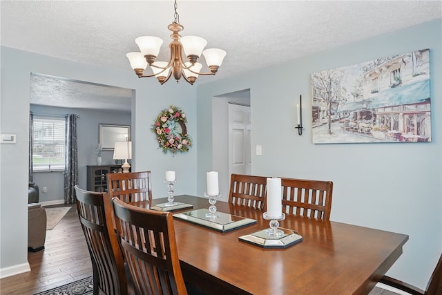 dining area with a chandelier, baseboards, wood finished floors, and a textured ceiling
