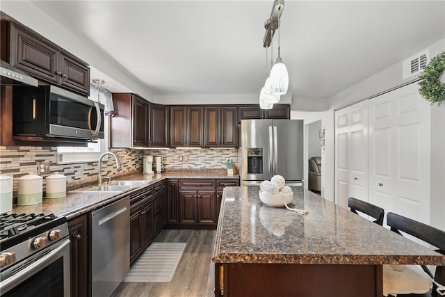 kitchen featuring a breakfast bar, decorative backsplash, stainless steel appliances, and a sink
