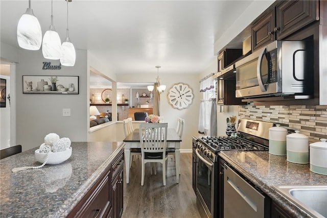 kitchen featuring tasteful backsplash, dark brown cabinets, wood finished floors, appliances with stainless steel finishes, and a notable chandelier