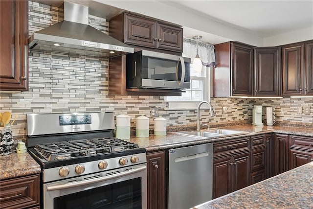 kitchen featuring stainless steel appliances, a sink, tasteful backsplash, dark brown cabinets, and wall chimney range hood