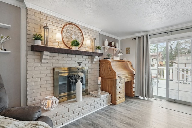 living room featuring a fireplace, wood finished floors, a textured ceiling, and ornamental molding
