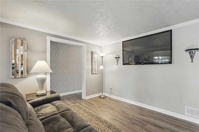 living room featuring wood finished floors, visible vents, crown molding, baseboards, and a textured ceiling