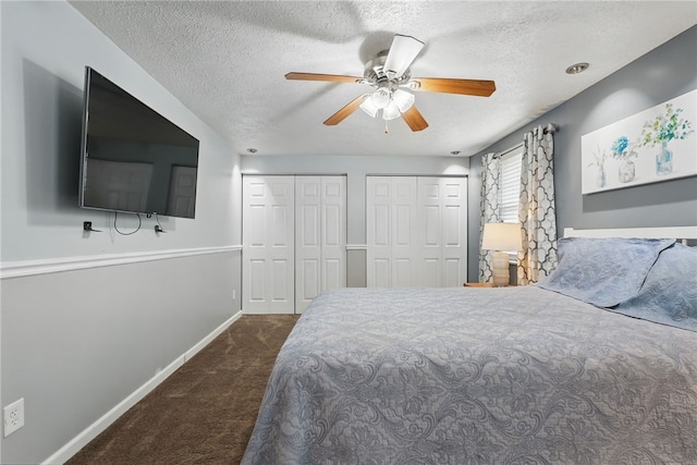 carpeted bedroom featuring a textured ceiling, multiple closets, a ceiling fan, and baseboards