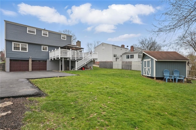 view of yard featuring a storage unit, fence, an attached garage, stairs, and a deck