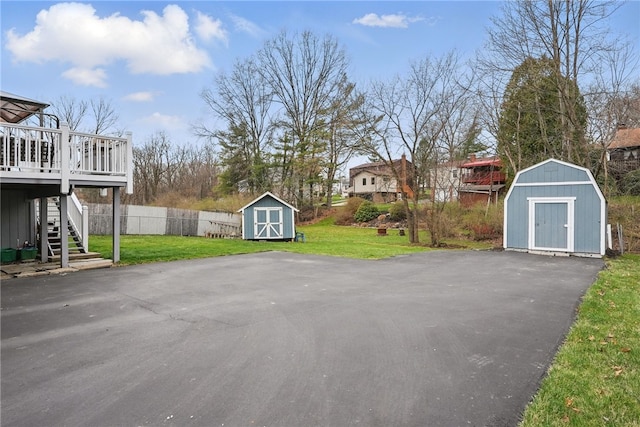 view of patio with stairway, fence, a storage shed, an outbuilding, and a deck